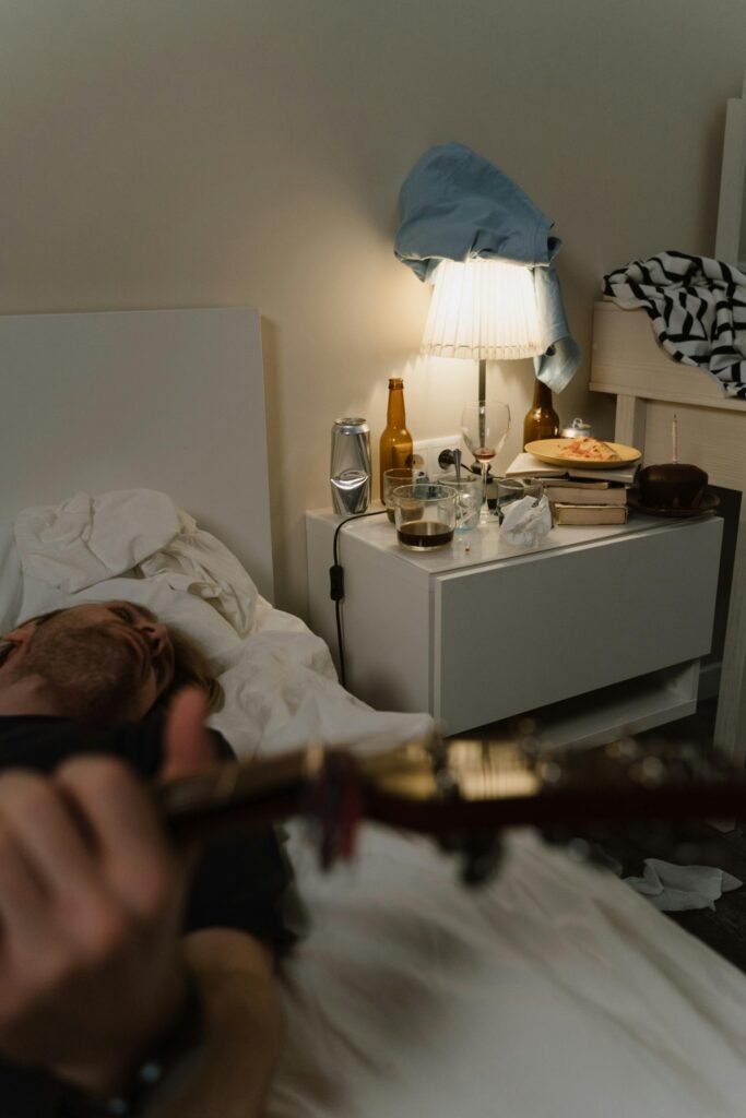 A person playing the guitar under the bedroom clutter