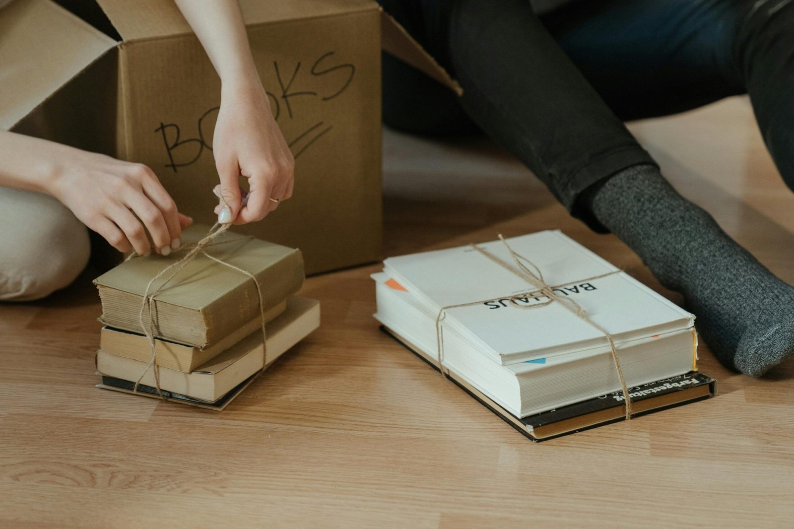 a person tying a string on books, because it follows our spring cleaning hacks